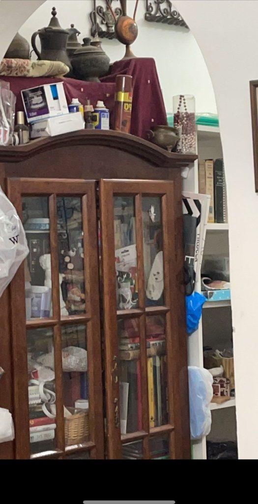 ויטרינה וארון עמוסים בחפצים בדירת ירושה לפני פינוי